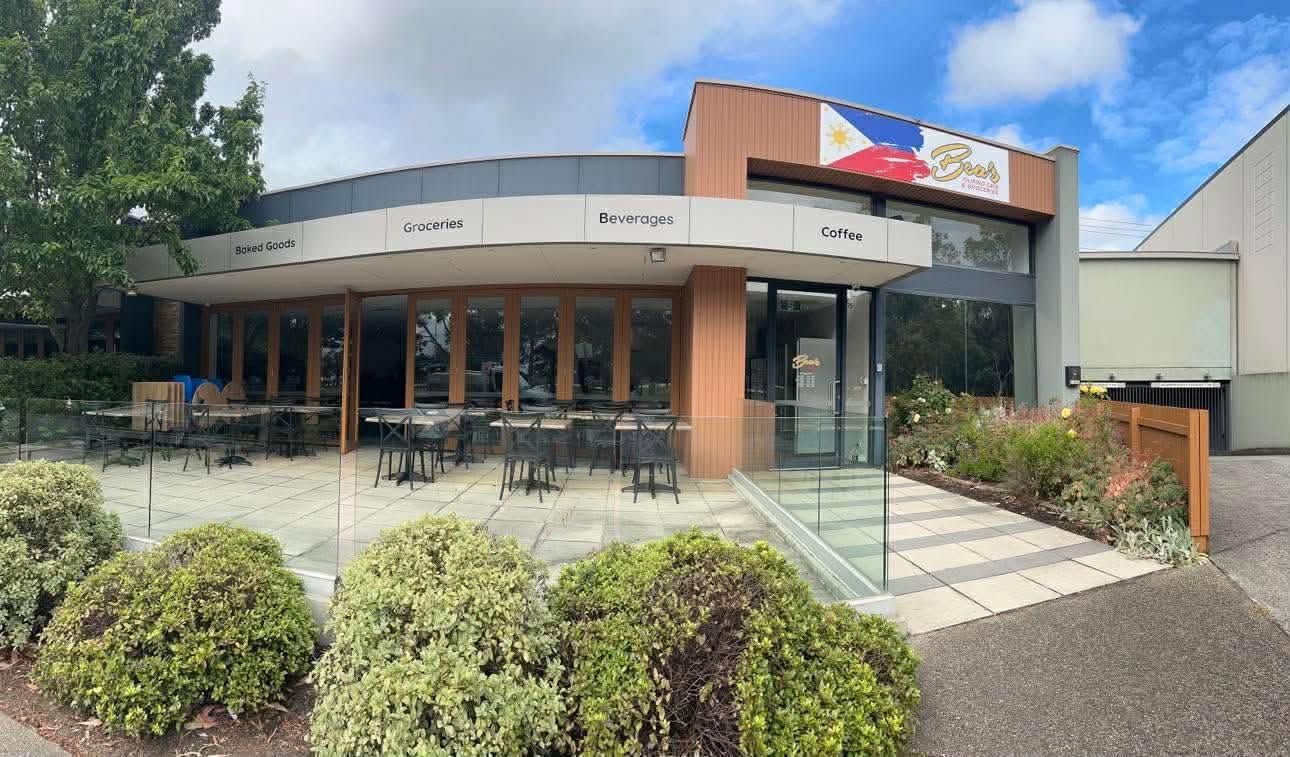 Bea's Asian Mart and Cafe exterior — modern glass building with outdoor seating and Philippine flag signage